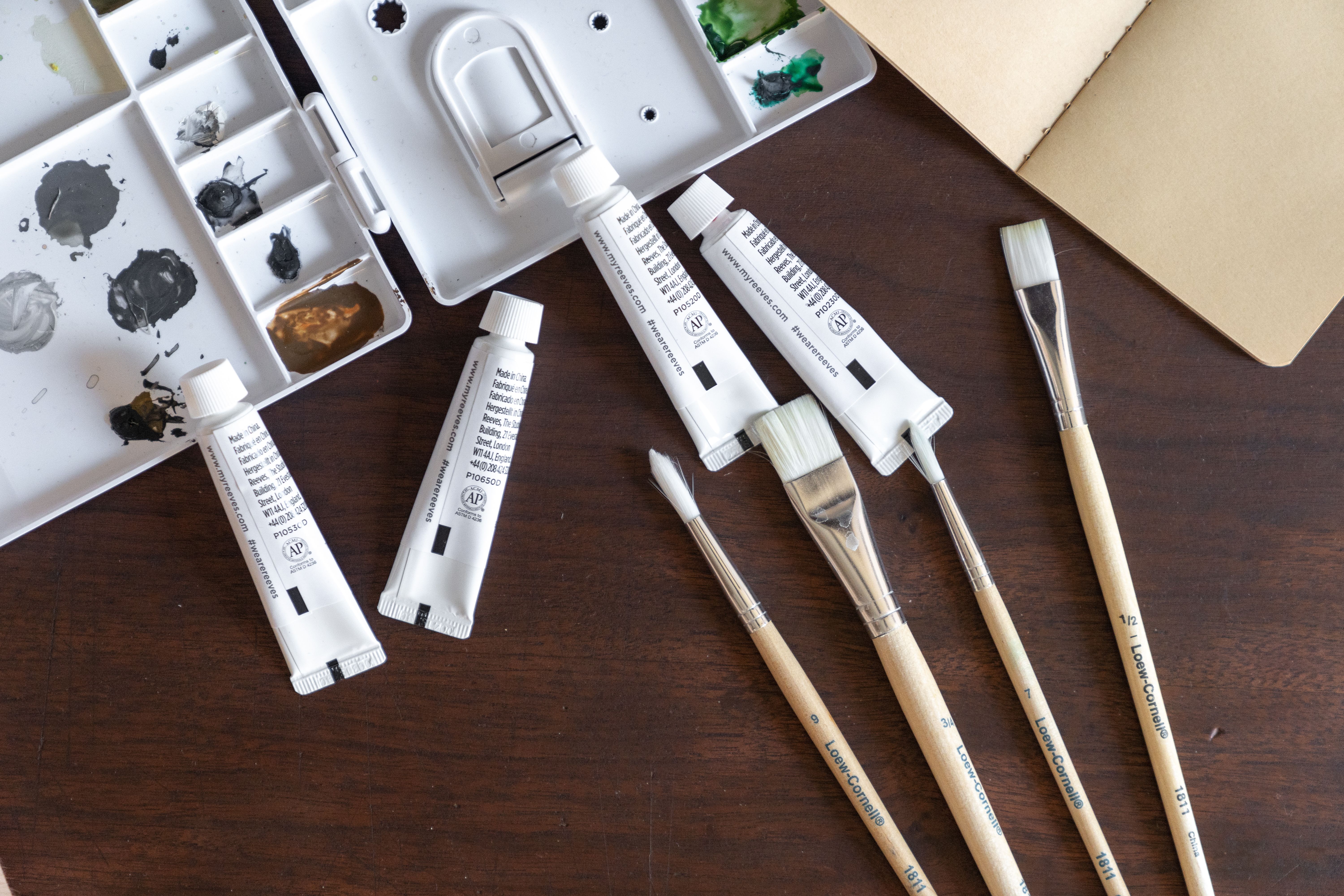 Fine artist paint brushes, paint tubes and studio sketchbook